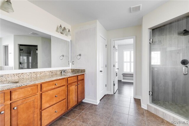 bathroom with walk in shower, vanity, and tile patterned flooring