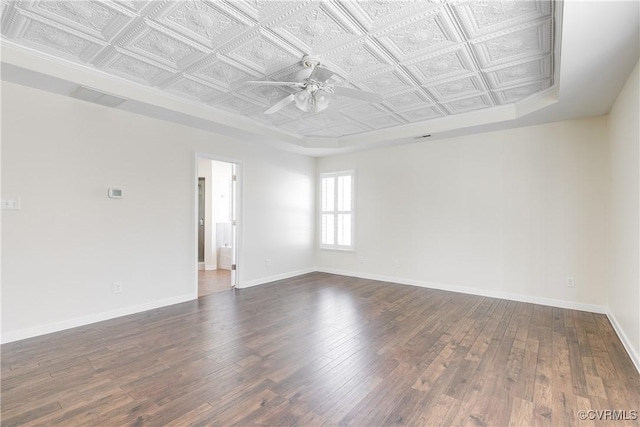 empty room featuring ceiling fan, an ornate ceiling, baseboards, and dark wood finished floors