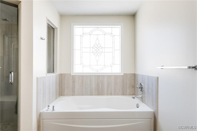 bathroom featuring a shower with door and a bath