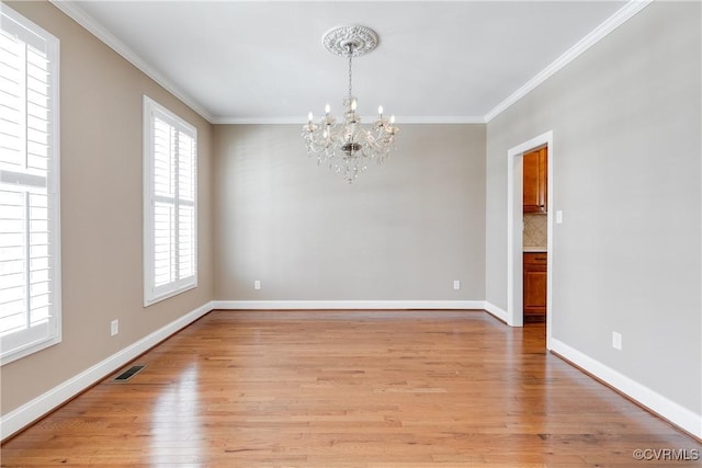 unfurnished room with crown molding, visible vents, an inviting chandelier, light wood-type flooring, and baseboards