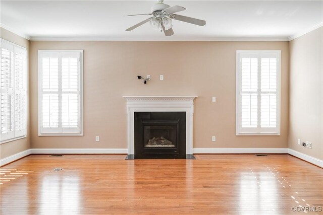 unfurnished living room featuring ceiling fan, a healthy amount of sunlight, ornamental molding, and light hardwood / wood-style flooring