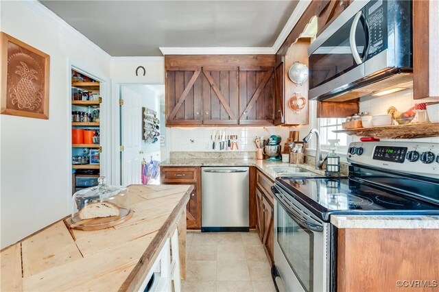 kitchen with appliances with stainless steel finishes, ornamental molding, decorative backsplash, and sink