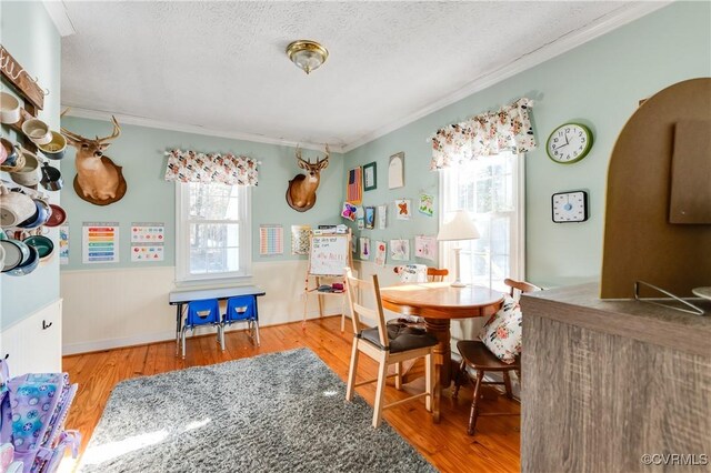 dining area with hardwood / wood-style floors, a textured ceiling, and ornamental molding