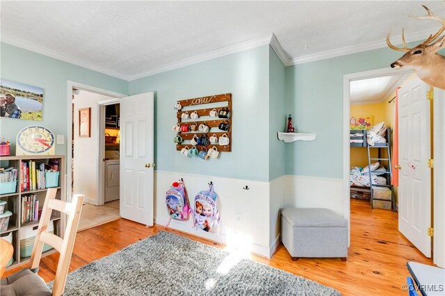 game room with washer / clothes dryer, hardwood / wood-style floors, a textured ceiling, and ornamental molding