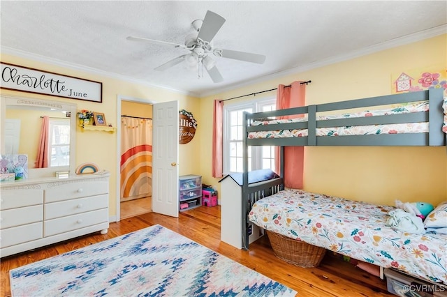 bedroom featuring a textured ceiling, ceiling fan, light wood-type flooring, and crown molding