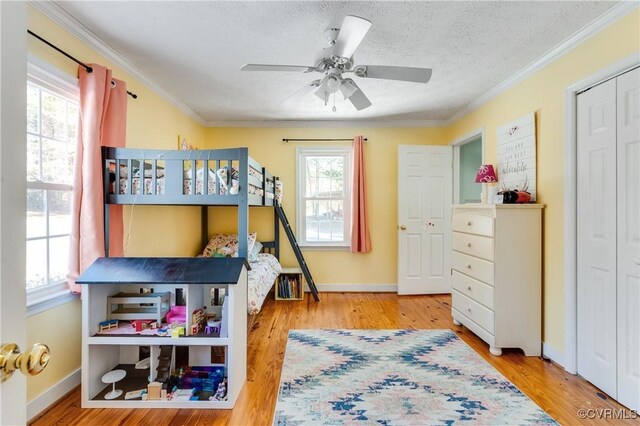 bedroom with a textured ceiling, ceiling fan, crown molding, and wood-type flooring