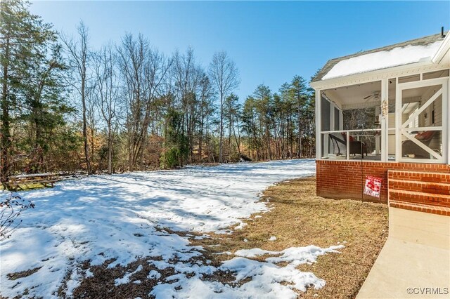 yard layered in snow featuring a sunroom