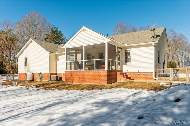 snow covered rear of property with central AC unit, ceiling fan, and a sunroom