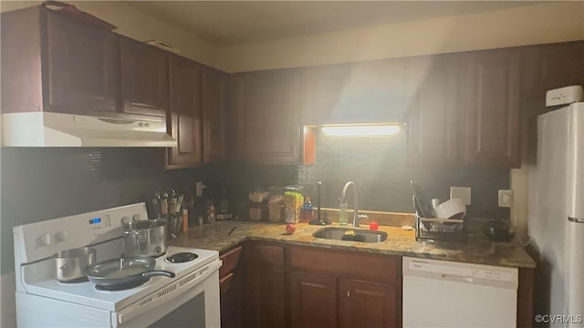 kitchen featuring light stone countertops, sink, and white appliances