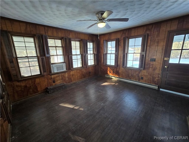 empty room featuring cooling unit, a baseboard heating unit, ceiling fan, and dark wood-type flooring