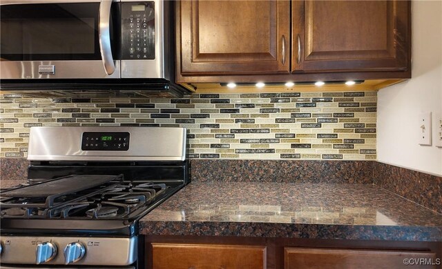 kitchen featuring tasteful backsplash, appliances with stainless steel finishes, and dark stone counters