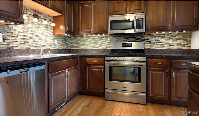 kitchen with decorative backsplash, appliances with stainless steel finishes, sink, and light hardwood / wood-style flooring