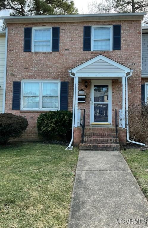 view of front facade with brick siding and a front lawn