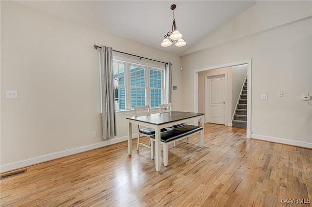 dining room with light hardwood / wood-style floors, vaulted ceiling, and a chandelier