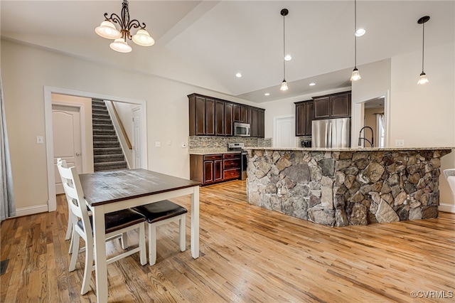 kitchen with appliances with stainless steel finishes, pendant lighting, dark brown cabinets, and backsplash