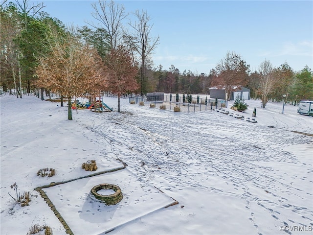 yard layered in snow with a fire pit and a storage shed