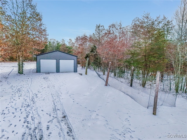 yard covered in snow featuring a garage and an outbuilding