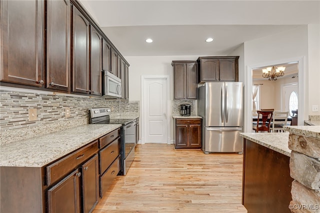 kitchen with light hardwood / wood-style floors, tasteful backsplash, dark brown cabinets, a chandelier, and appliances with stainless steel finishes