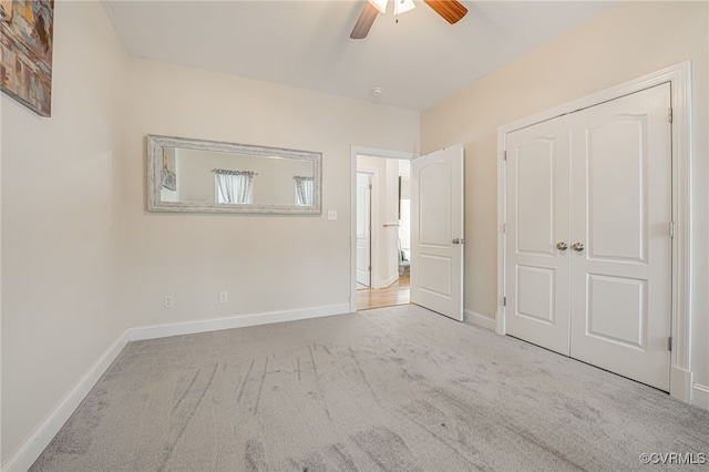 unfurnished bedroom featuring ceiling fan, a closet, and light carpet