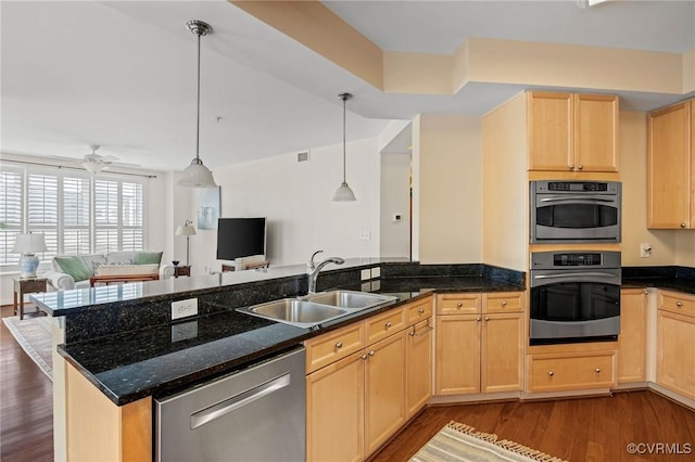 kitchen featuring sink, stainless steel appliances, light brown cabinetry, and hanging light fixtures