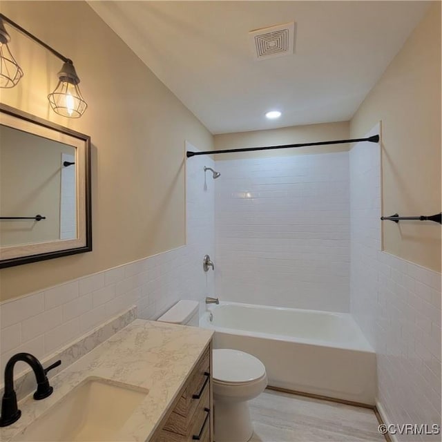 full bathroom featuring tile walls, tiled shower / bath combo, vanity, wood-type flooring, and toilet