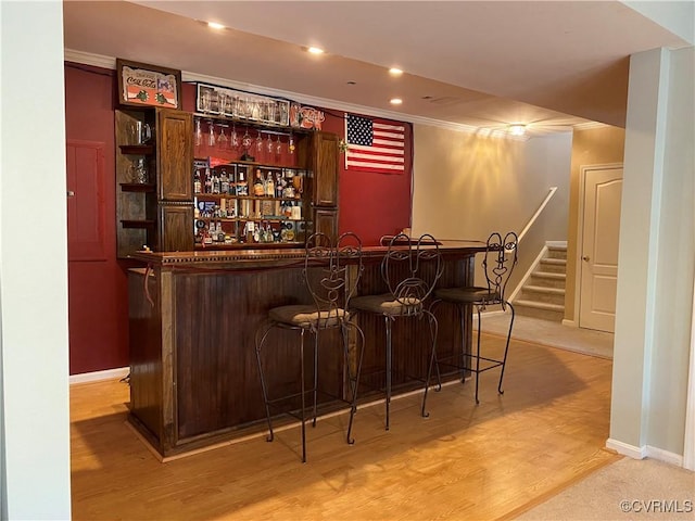 bar featuring light wood-type flooring and ornamental molding