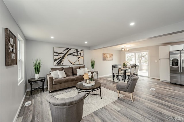 living room with light wood-type flooring and a chandelier