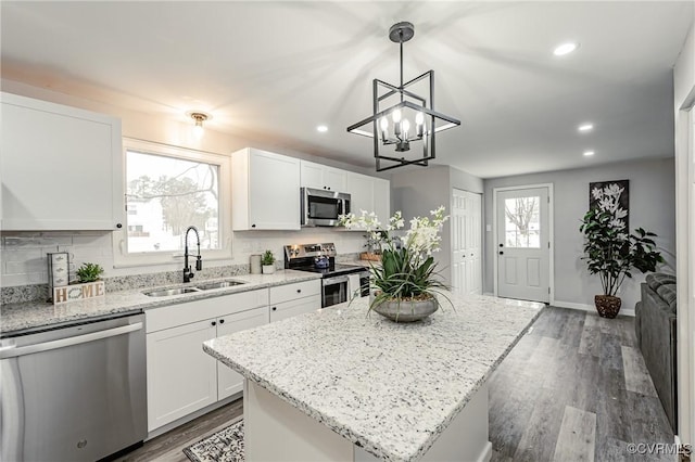 kitchen with a center island, sink, white cabinetry, hanging light fixtures, and appliances with stainless steel finishes