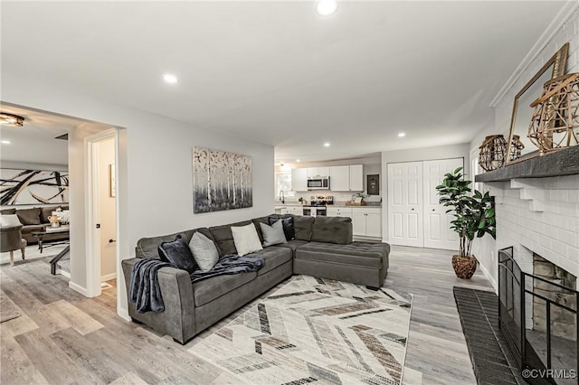 living room with light hardwood / wood-style floors, sink, and a fireplace