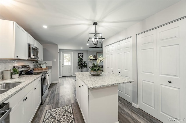 kitchen featuring hanging light fixtures, stainless steel appliances, white cabinets, and a kitchen island