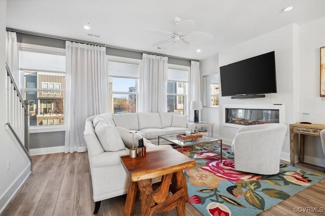 living room with ceiling fan, plenty of natural light, and light hardwood / wood-style floors