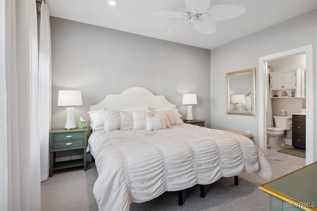 carpeted bedroom with ensuite bath and ceiling fan