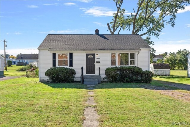 bungalow featuring a front lawn and a storage shed