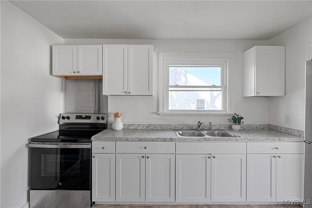 kitchen featuring electric stove, white cabinets, sink, and a textured ceiling