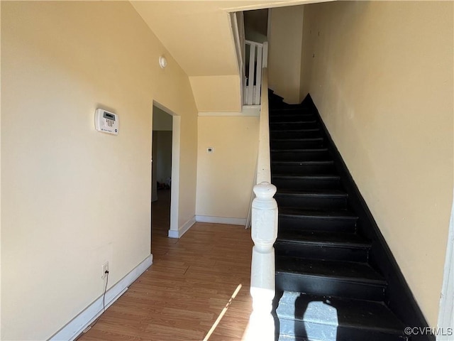 staircase with wood-type flooring and vaulted ceiling