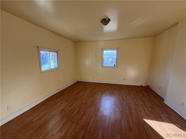 spare room featuring a wealth of natural light and dark hardwood / wood-style floors