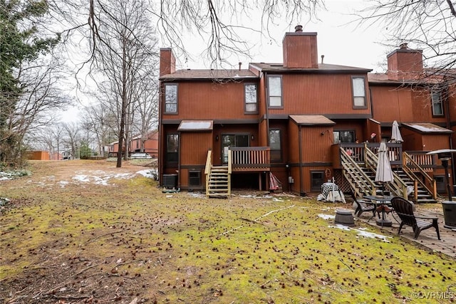 rear view of house featuring central AC and a lawn