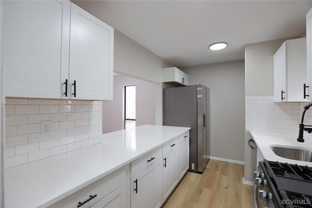 kitchen featuring tasteful backsplash, white cabinets, light wood-type flooring, and stainless steel appliances