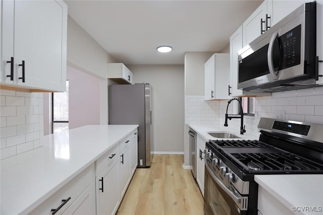 kitchen featuring light wood-type flooring, stainless steel appliances, white cabinets, and sink