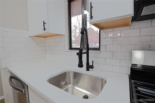 kitchen with decorative backsplash, dishwasher, white cabinets, and sink