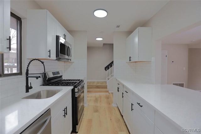 kitchen with sink, white cabinets, and stainless steel appliances