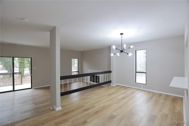 empty room with an inviting chandelier and light hardwood / wood-style flooring