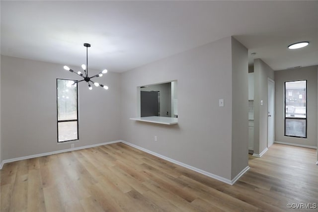 spare room with light wood-type flooring and a chandelier