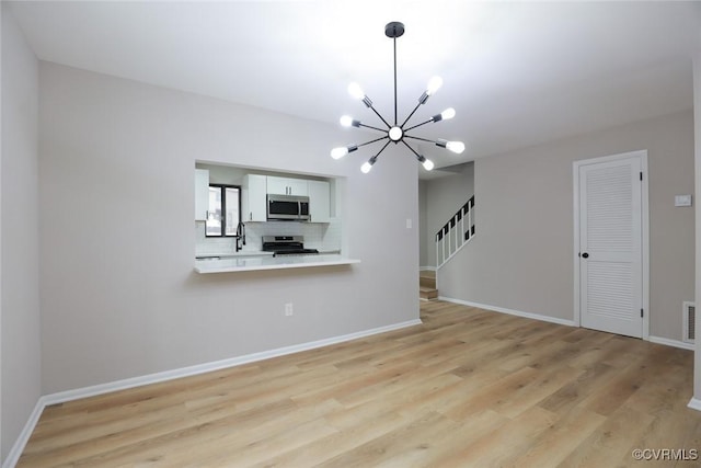 unfurnished living room featuring a notable chandelier and light wood-type flooring