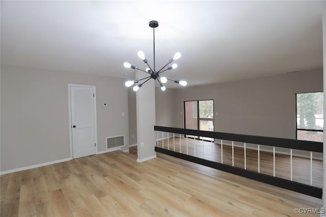 unfurnished room with a chandelier and light hardwood / wood-style flooring