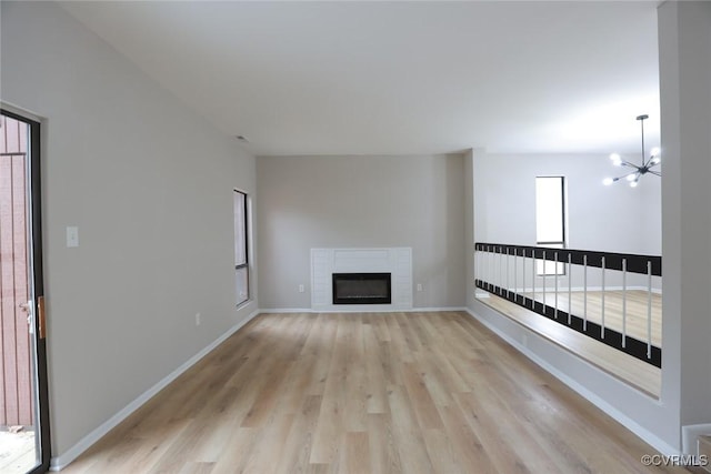 unfurnished living room featuring light hardwood / wood-style floors, a chandelier, and a fireplace