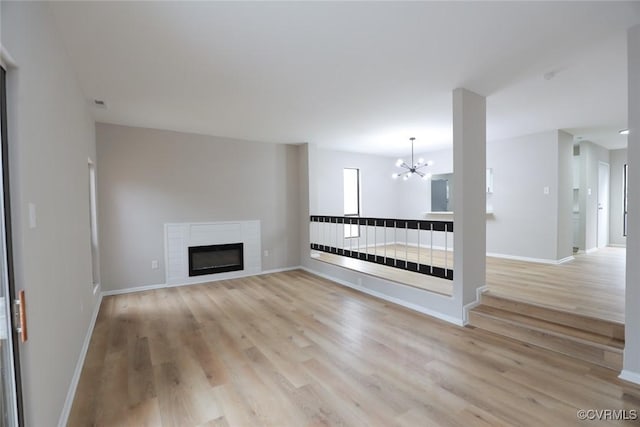 unfurnished living room with a chandelier and light hardwood / wood-style floors