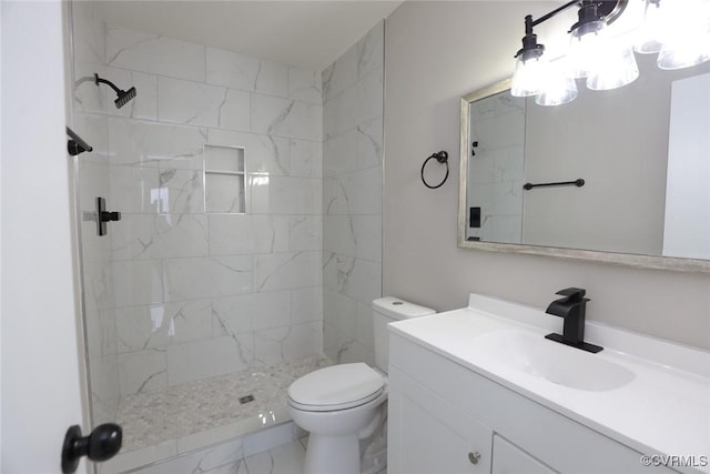 bathroom with toilet, vanity, and a tile shower