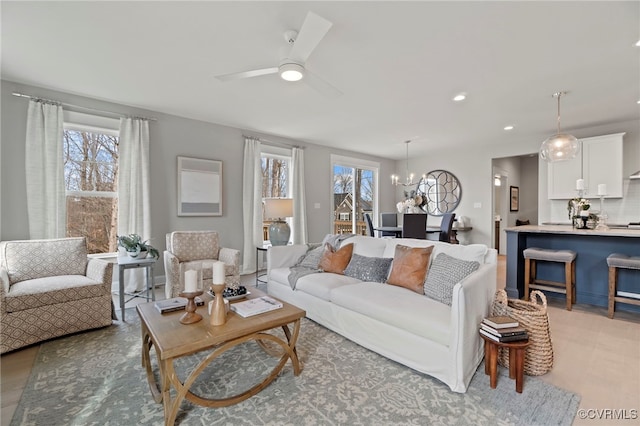 living room with light wood-type flooring and ceiling fan with notable chandelier