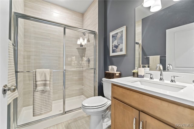 bathroom featuring toilet, vanity, and a shower with door